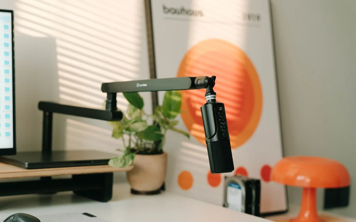 A desktop microphone beside a leafy plant in a home workspace.